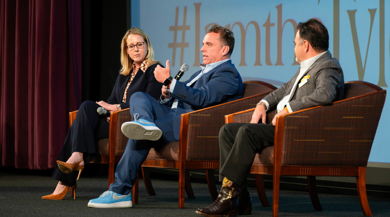 two men and a woman sitting in chairs on stage