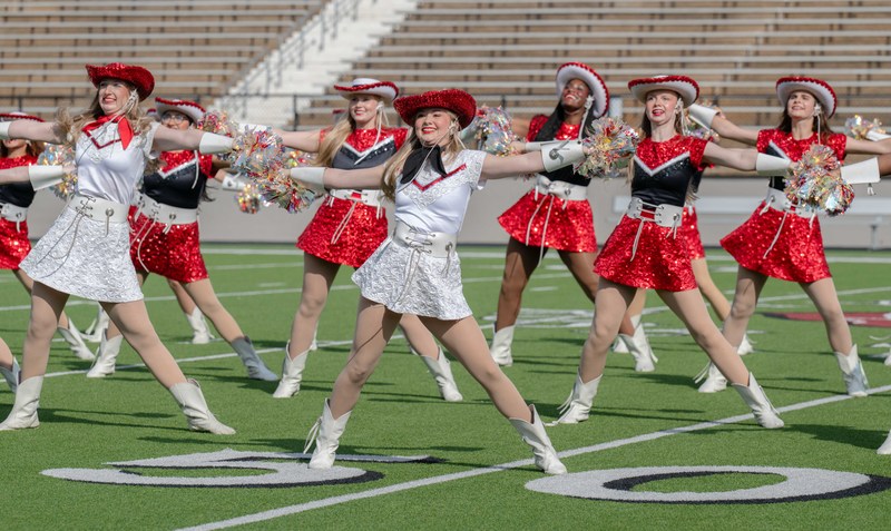 drill team in red uniforms on football field