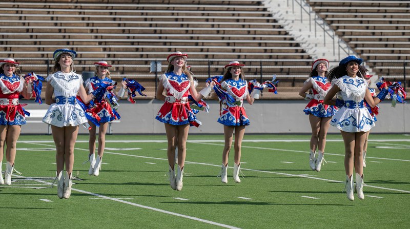 drill team in red. white, blue uniforms on football field
