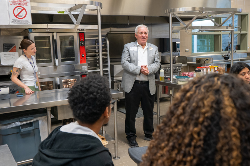 man talking to students in culinary class kitchen