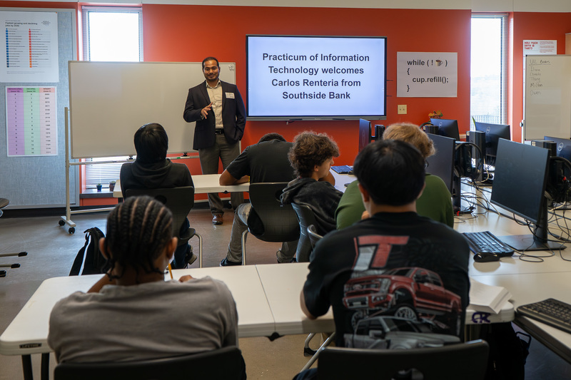 man talking to male students in classroom