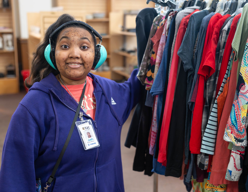 teen girl standing by clothes rack