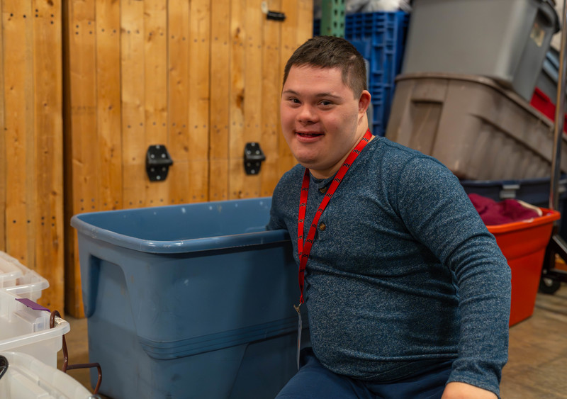 teen boy putting something in plastic tote