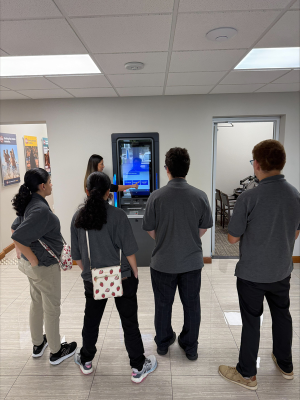 woman teaching teens how to use ATM