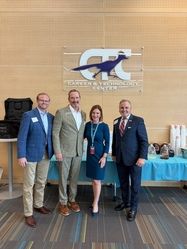 three men and a woman standing in front of a table