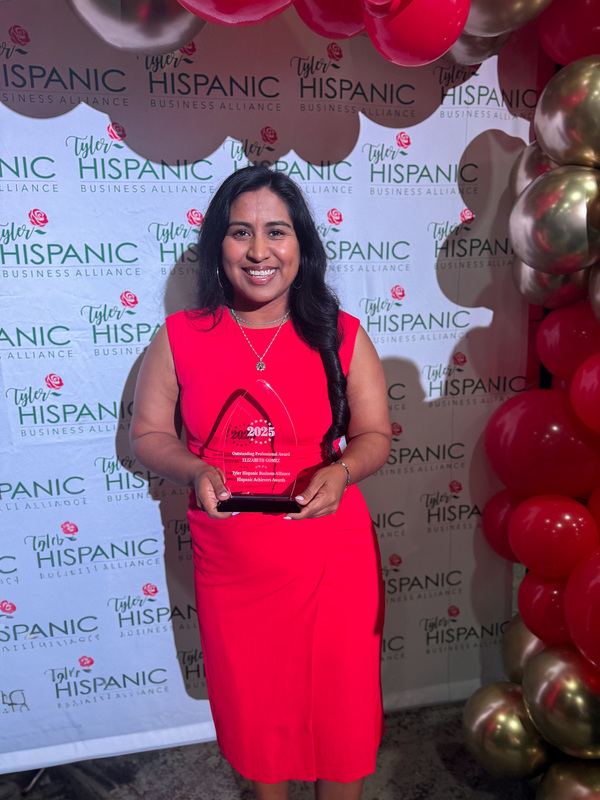 Hispanic woman in red dress holding plaque