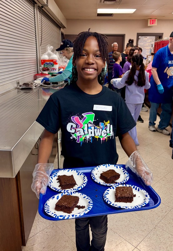 middle school age child holding tray with brownies