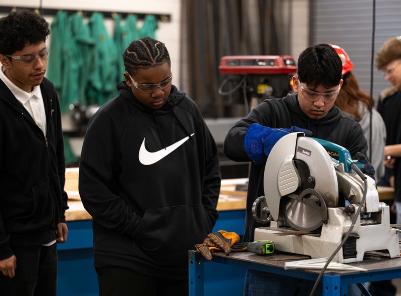 teen boys working with saw in shop class