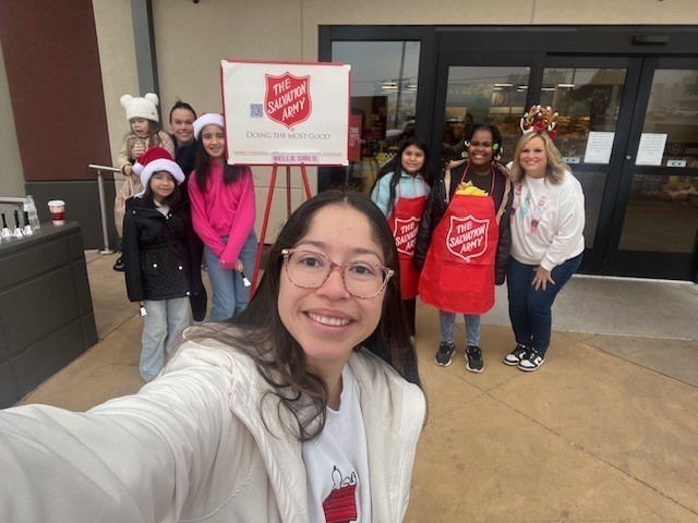 elementary age girls ringing Salvation Army bell outside a store