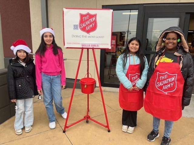 elementary age girls ringing Salvation Army bell outside a store