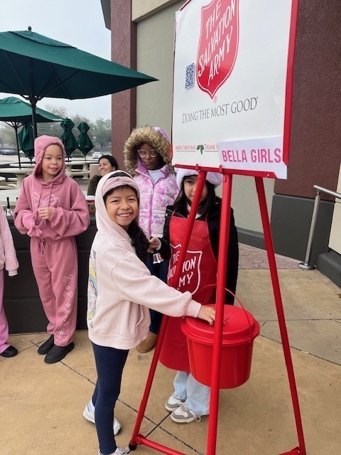 elementary age girls ringing Salvation Army bell outside a store