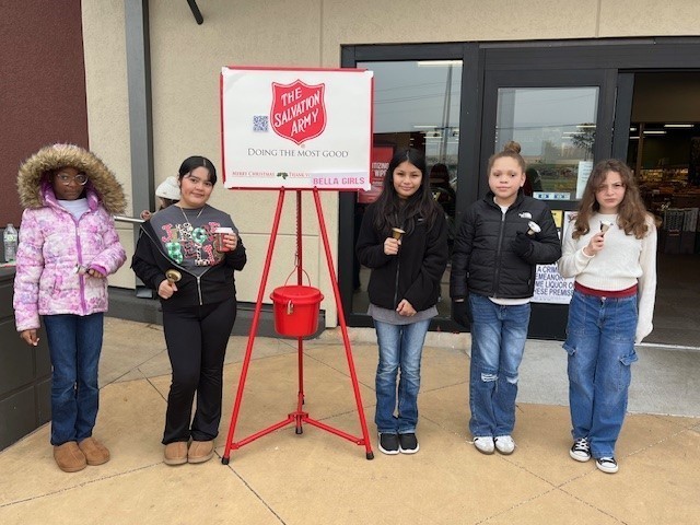 elementary age girls ringing Salvation Army bell outside a store