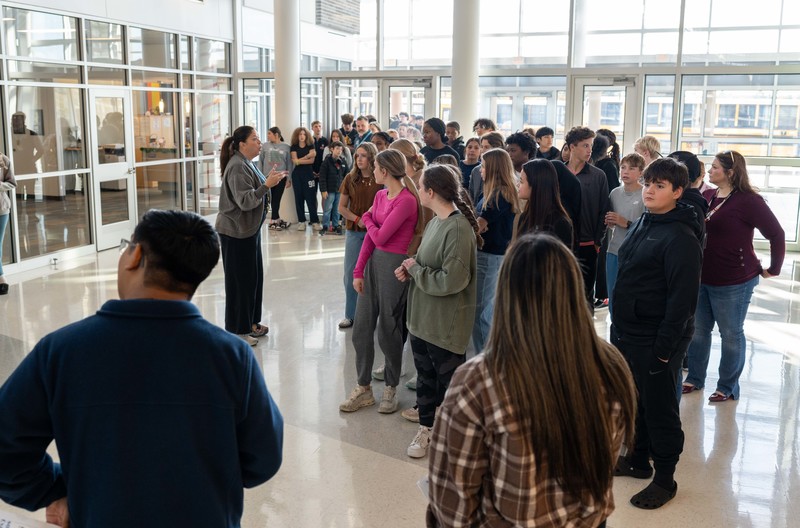 woman talking to group of teens in a school hallway