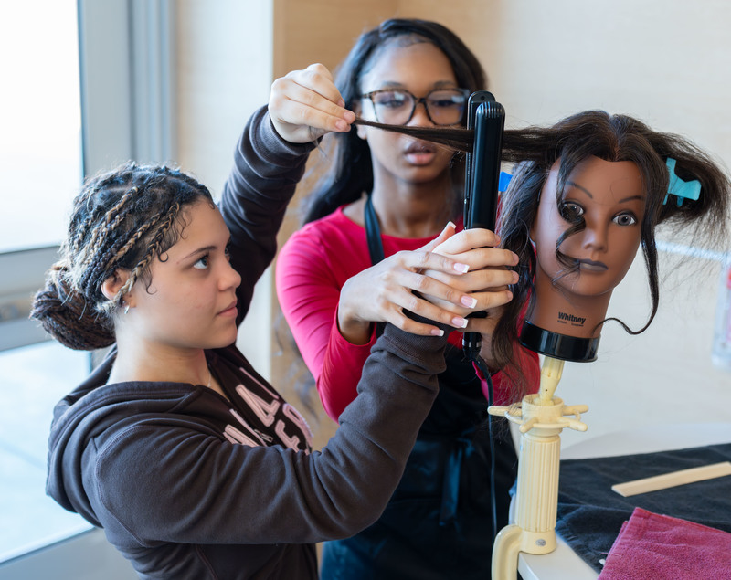 teen girls doing hair on a mannequin