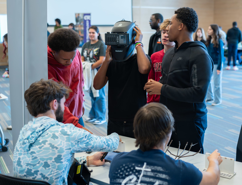 teen boys talking and one of them wearing a welders helmet