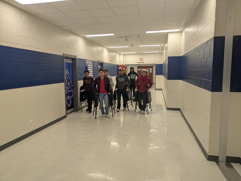 teens carrying chairs down hallway