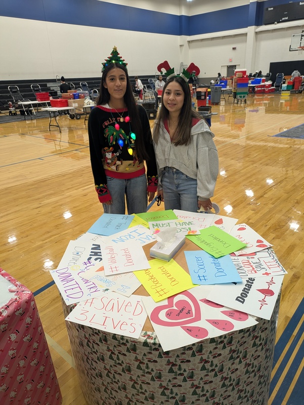 teens standing behind table with decorated signs