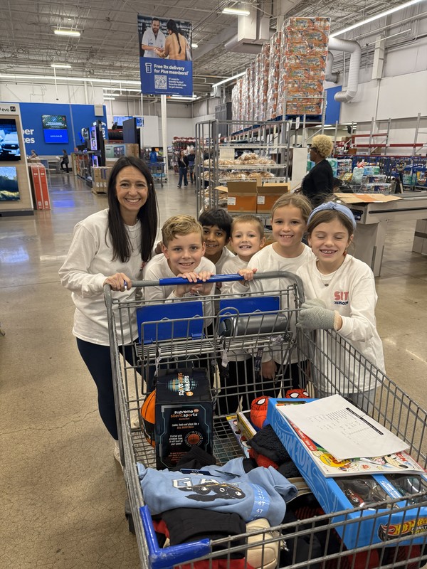 elementary kids and woman with shopping cart full of items