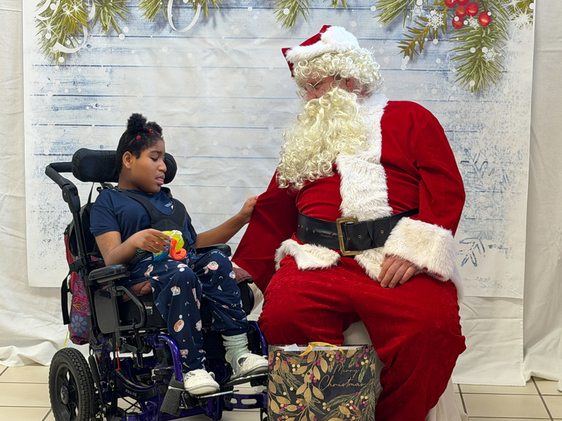 child in wheelchair holding Santa's arm