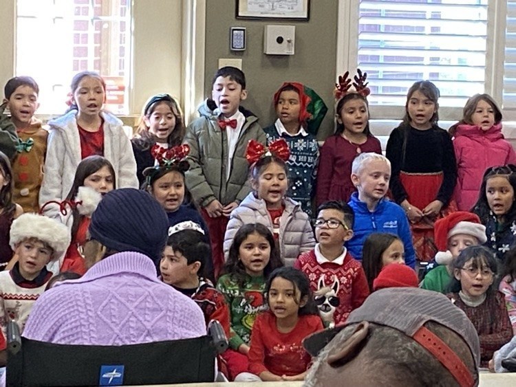 elementary age kids in Christmas outfits singing at nursing home