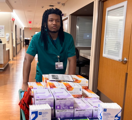 teen boy pushing cart with supplies down a hallway