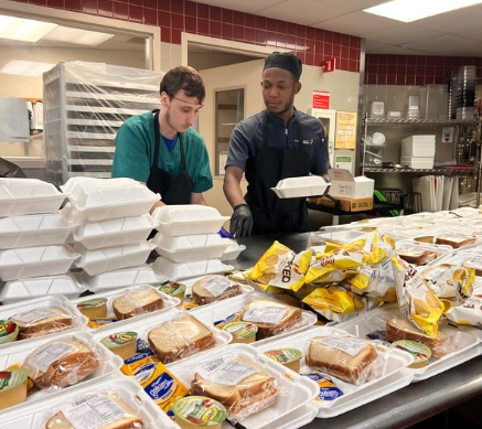 two men packing box lunches in cafeteria
