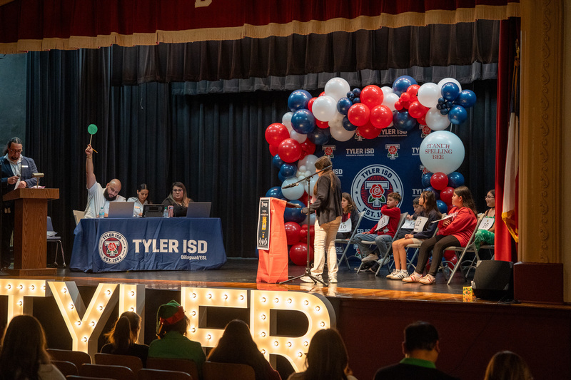 group o fkids and judges on stage for a spelling bee
