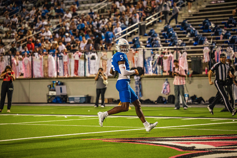 teen boy in blue football uniform running on field