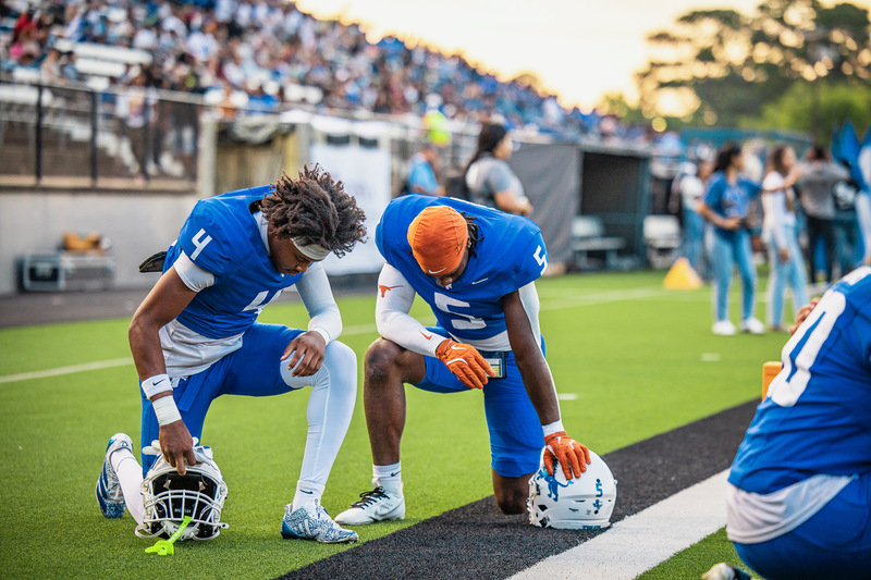 two teen boys praying on football sideline