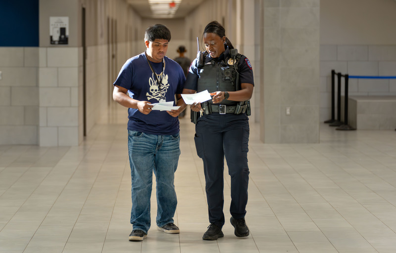 woman in police uniform walking with male teen looking at papers