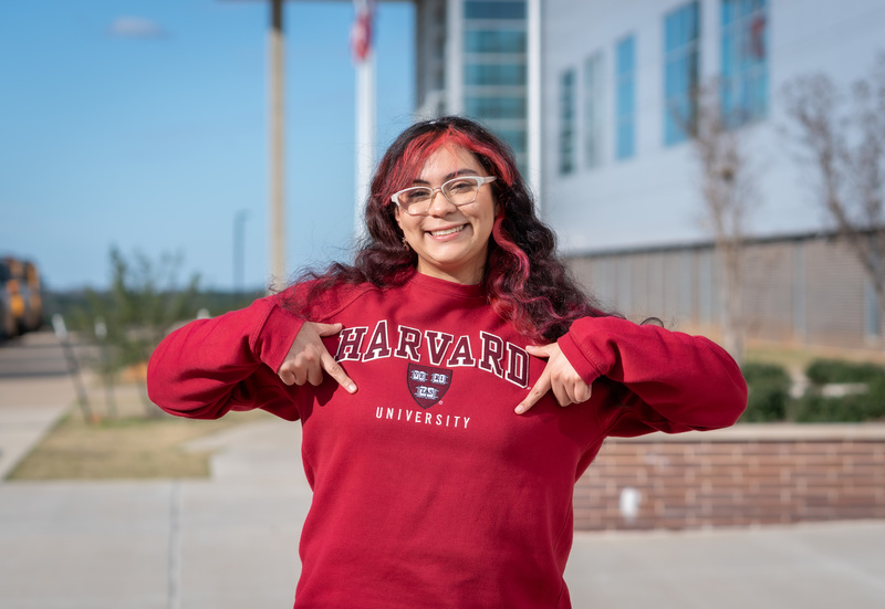 teen girl pointing at her Harvard sweatshirt she's wearing