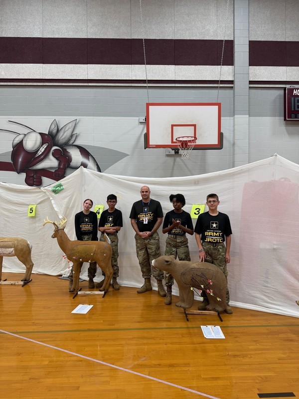 teen boys and girls standing behind archery targets shaped like a deer and a bear