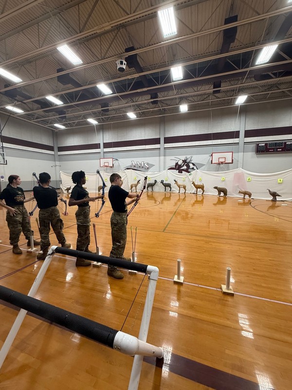 teen boys and girls practice shooting archery targets shaped like a deer and a bear
