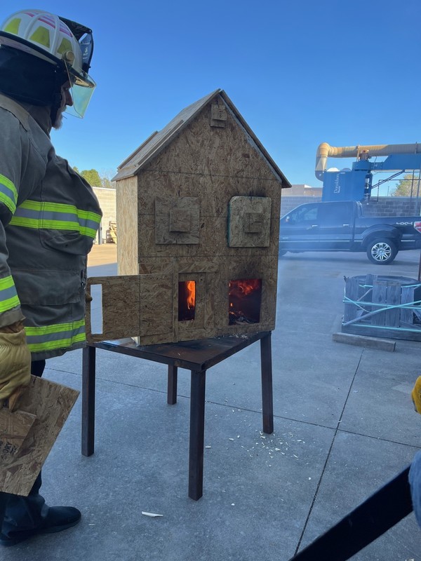 Teacher using a doll house to teach a fire control lesson.