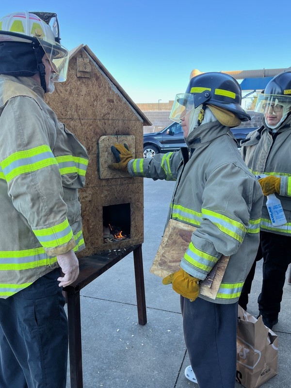 Teacher using a doll house to teach a fire control lesson.