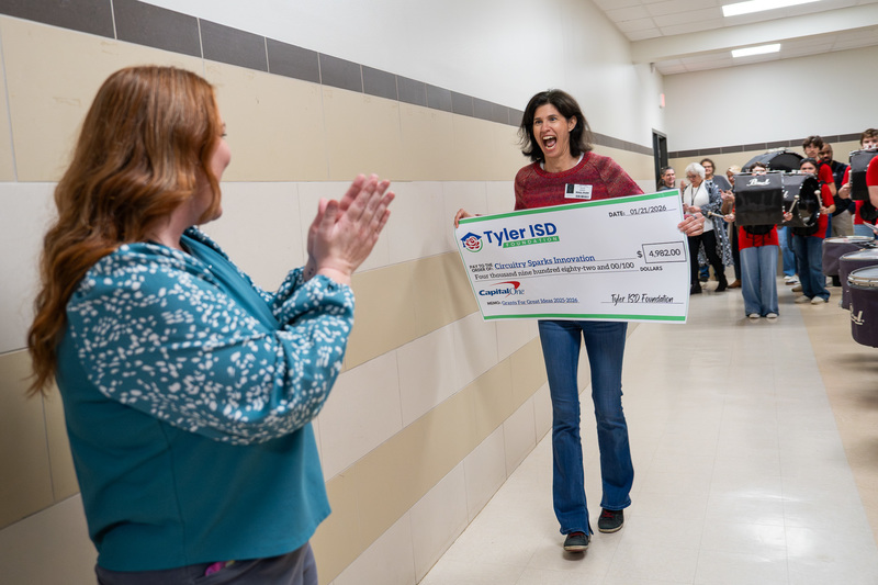 woman walking down hallway with giant check