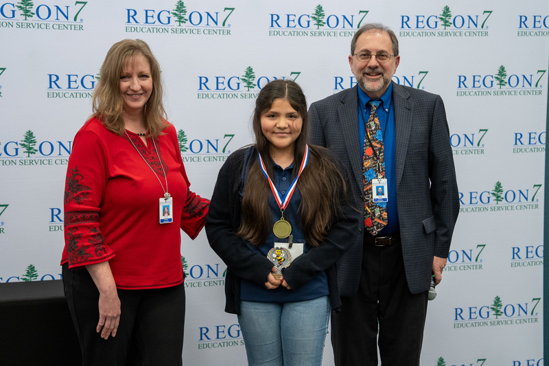 man and woman standing next to child holding trophy