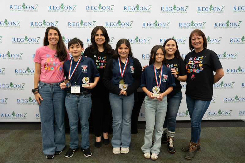 boys and girls holding trophies and medals with women standing behind them