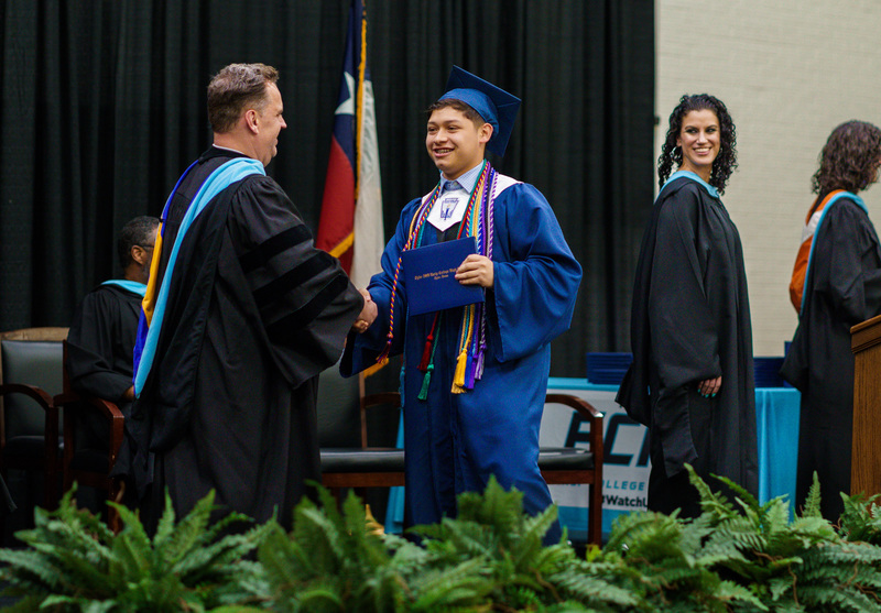 teen boy in cap and gown shaking hands with man