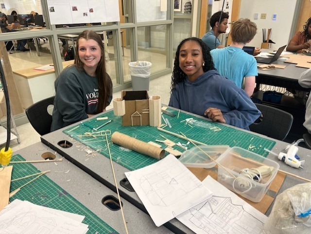 teen girls sitting at table constructing project with cardboard