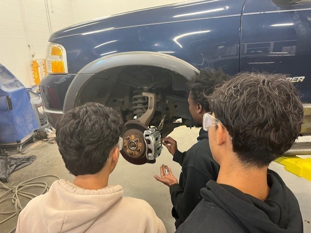 teen boys working on axle of car
