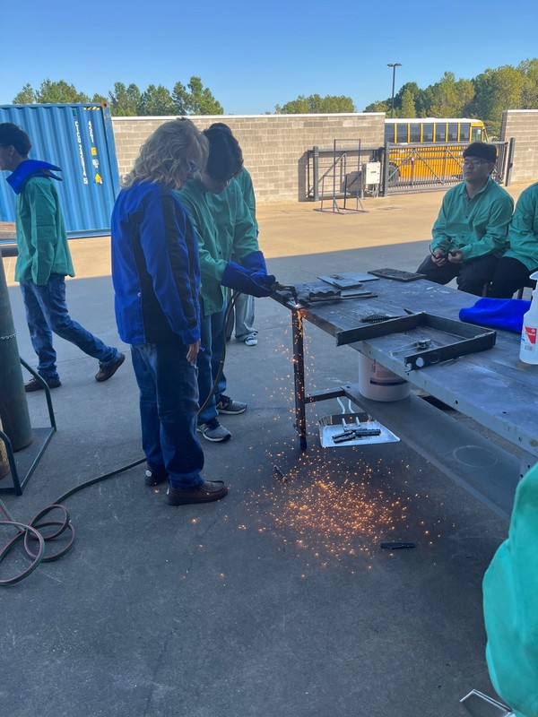 teens welding on a table, sparks flying