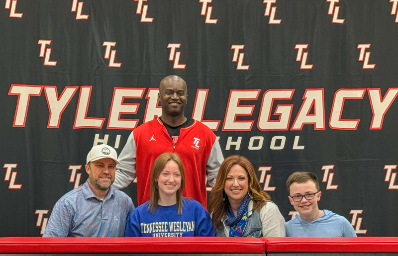 teen girl and her family and coach at a table where she signed to play volleyball in college