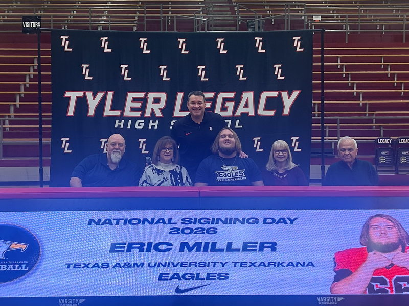 teen boy and his family and coach at table where he signed to play football in college