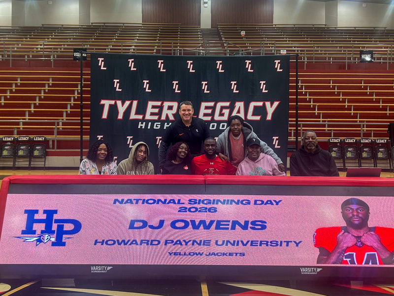 teen boy and his family and coach at table where he signed to play football in college