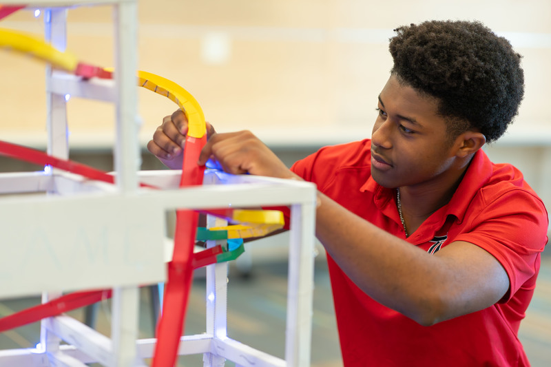 teen boy working on rollercoaster made from paper and tape