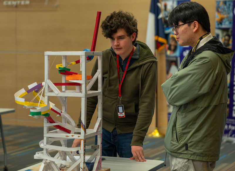 teen boys looking at roller coaster made from paper and tape
