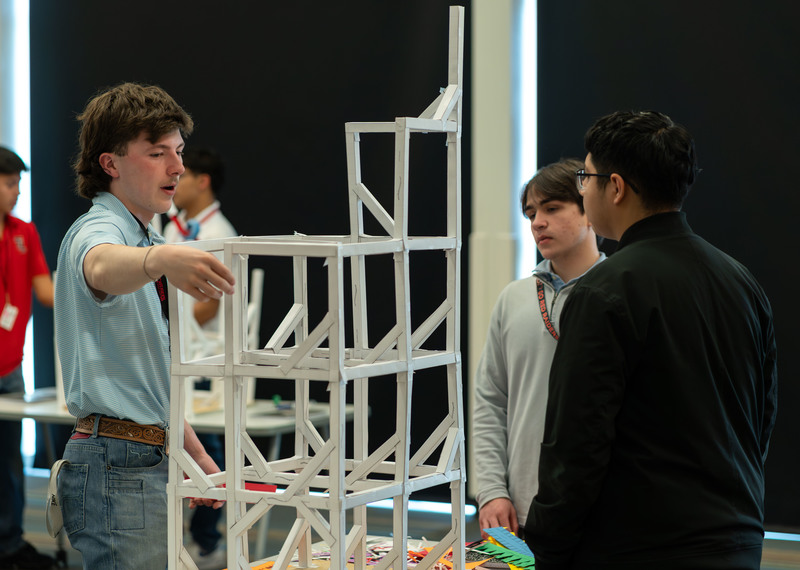 teen boys looking at roller coaster made from paper and tape