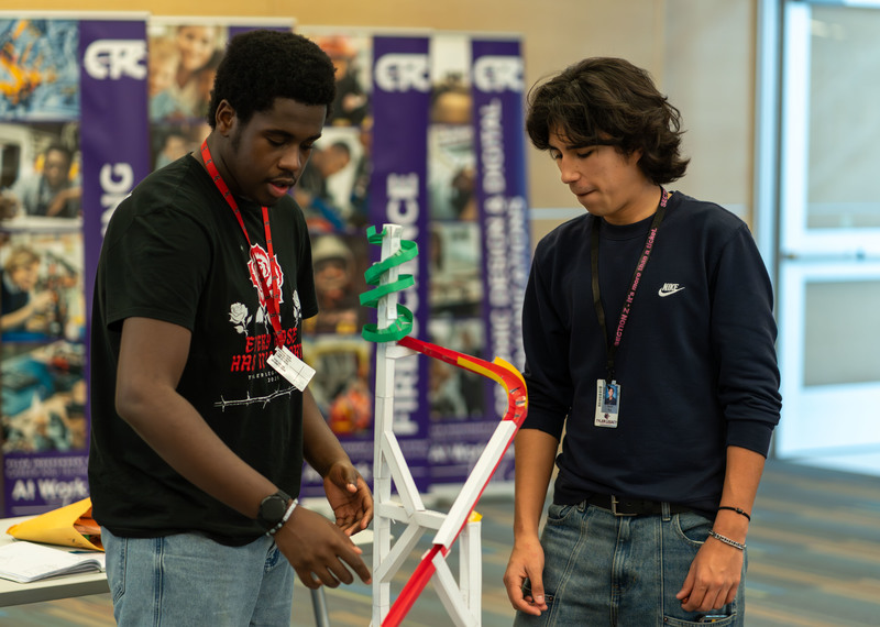 teen boys looking at roller coaster made from paper and tape