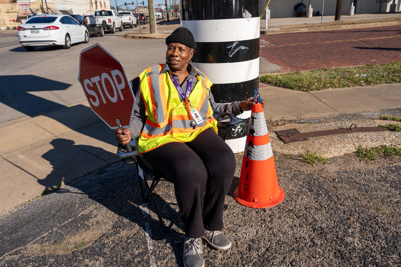 woman wearing yellow vest holding stop sign while sitting in a chair